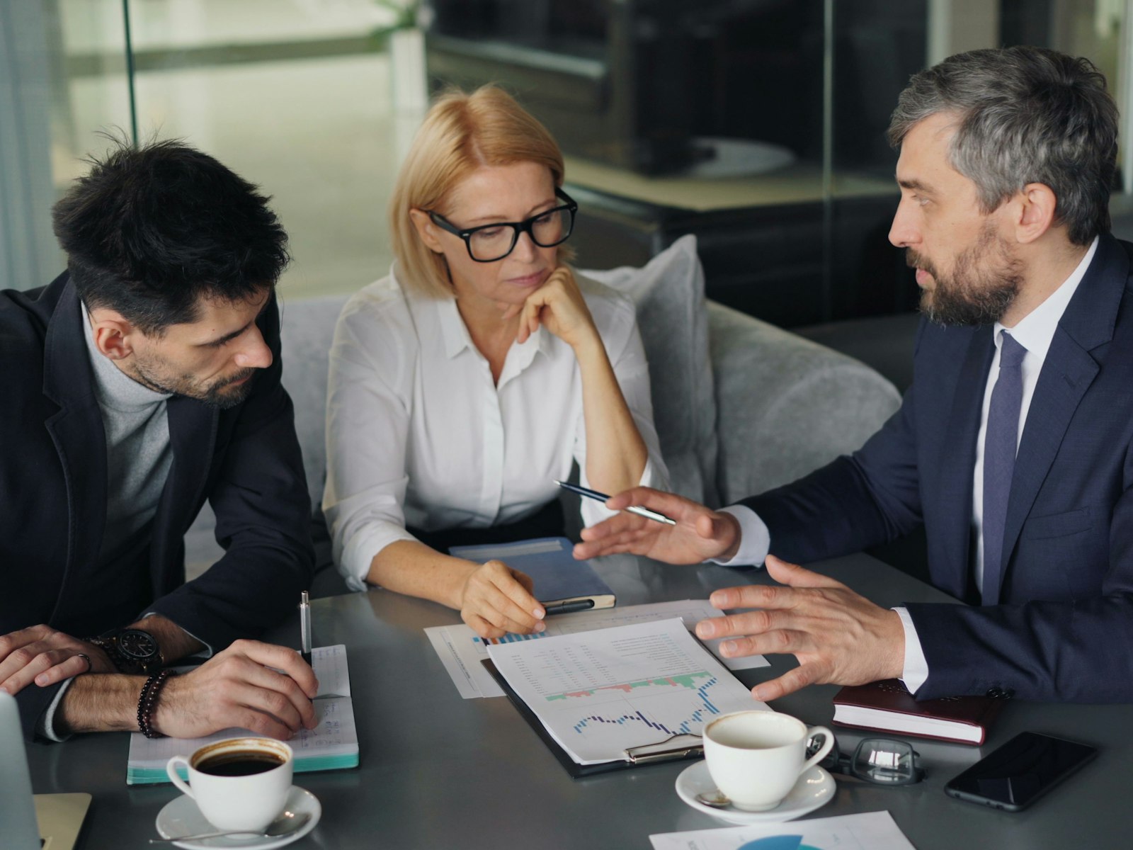 Trois conseillers en costume étudient un plan financier autour d'une table